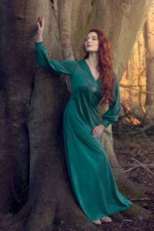 Photograph of a woman in a princess dress standing against a tree